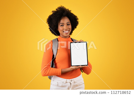 Friendly young woman with a natural afro hairstyle presents a blank tablet screen with a smile 112718652