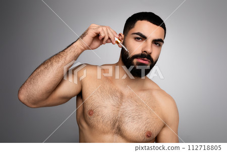Attractive arab guy using hair growth for his beard 112718805