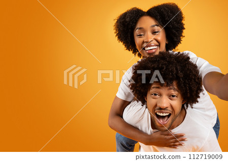 Cool millennial african american couple taking selfie on orange Cool millennial african american couple taking selfie on orange 112719009
