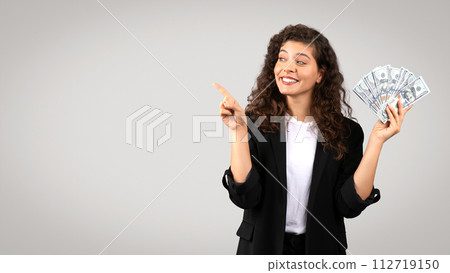 Confident businesswoman holding money and pointing at free space Confident businesswoman holding money and pointing at free space 112719150