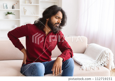 Upset indian man feel sudden back pain, home interior 112719151