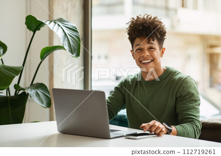 Cheerful millennial black man freelancer working at cozy cafe 112719261