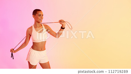 Smiling woman in activewear using a resistance band for her exercise routine 112719289