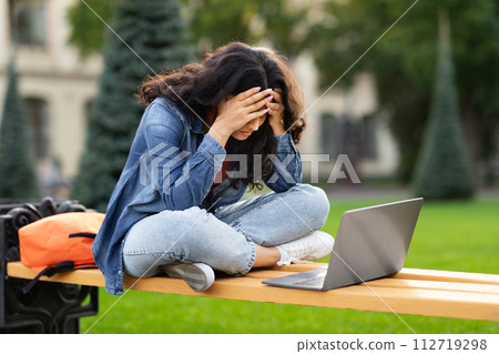 Stressed young Indian woman student studying with laptop 112719298