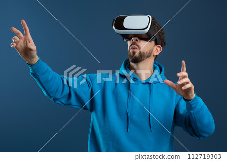 Engrossed man wearing virtual reality headset and gesturing with his hands Engrossed man wearing virtual reality headset and gesturing with his hands 112719303