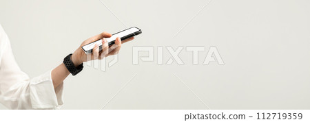 Close-up of a hand holding a smartphone with a white screen, featuring a woman in a white blouse Close-up of a hand holding a smartphone with a white screen, featuring a woman in a white blouse 112719359