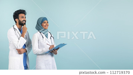 Confident muslim medical professionals in white coats looking at copy space 112719370
