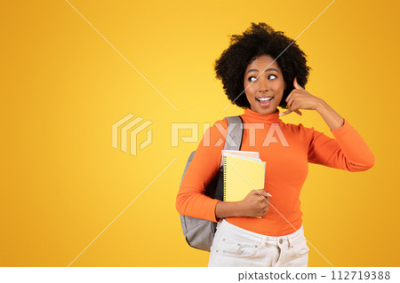 Amused young woman with afro hair, in an orange sweater and white pants Amused young woman with afro hair, in an orange sweater and white pants 112719388