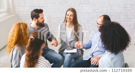 Diverse people sitting on chairs in circle holding hands Diverse people sitting on chairs in circle holding hands 112719389