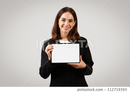 A cheerful, professional young woman confidently displays a blank tablet screen 112719393