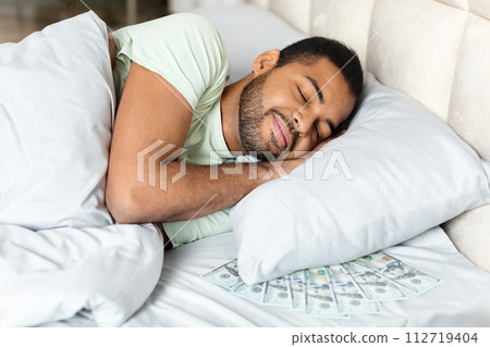 Black man sleeping with bunch of cash dollars under pillow 112719404