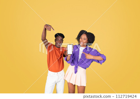 A young woman in a purple shirt and a young man in an orange shirt, both smiling A young woman in a purple shirt and a young man in an orange shirt, both smiling 112719424