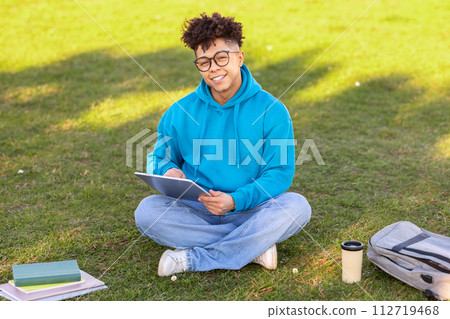 Brazilian student guy browsing internet on digital tablet learning outside 112719468