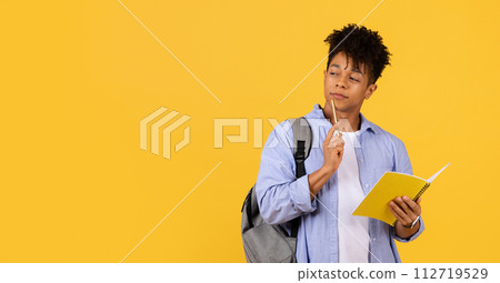 Thoughtful male student with notebook and pencil on yellow background Thoughtful male student with notebook and pencil on yellow background 112719529