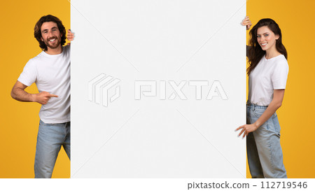 Cheerful young couple sharing a fun moment with a smartphone on a bright yellow background Cheerful young couple sharing a fun moment with a smartphone on a bright yellow background 112719546