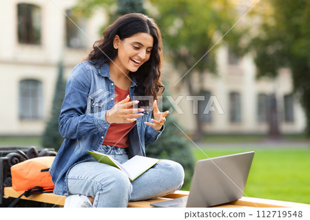 Eastern young lady student have online exam, using laptop outdoors Eastern young lady student have online exam, using laptop outdoors 112719548