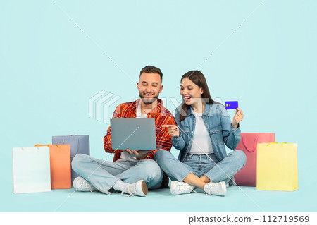 Couple Using Credit Card And Laptop Shopping Over Blue Backdrop Couple Using Credit Card And Laptop Shopping Over Blue Backdrop 112719569