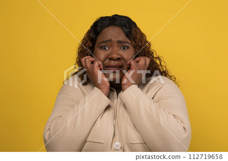 Scared millennial african american woman grimacing on yellow 112719658