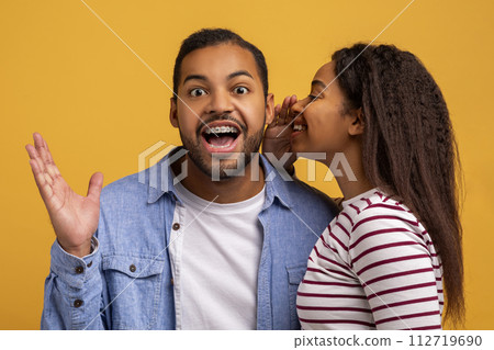 Big Secret. Young Black Woman Sharing News With Her Excited Boyfriend Big Secret. Young Black Woman Sharing News With Her Excited Boyfriend 112719690