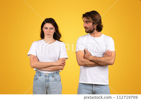 Serious young man and woman in plain white t-shirts and blue jeans standing with arms crossed Serious young man and woman in plain white t-shirts and blue jeans standing with arms crossed 112719709