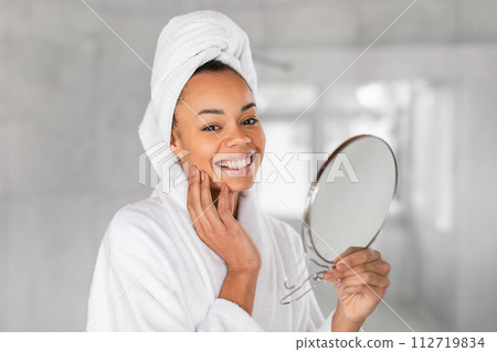 black lady holds round mirror touches face, portrait in bathroom black lady holds round mirror touches face, portrait in bathroom 112719834