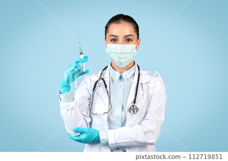 Serious woman doctor with syringe and safety gear Serious woman doctor with syringe and safety gear 112719851