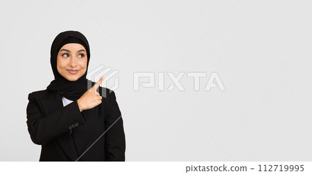 Happy businesswoman in hijab pointing right at free space with smile Happy businesswoman in hijab pointing right at free space with smile 112719995