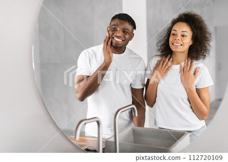 Smiling young African American couple in bathroom looking in mirror Smiling young African American couple in bathroom looking in mirror 112720109
