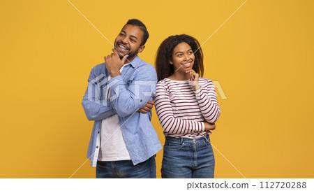 Portrait of pensive black couple standing against bright yellow background 112720288