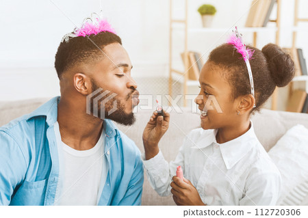 Little daughter applying lipstick on father's lips 112720306