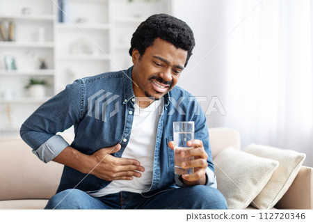 Black Man Suffering Sudden Chest Pain While Sitting On Couch At Home 112720346