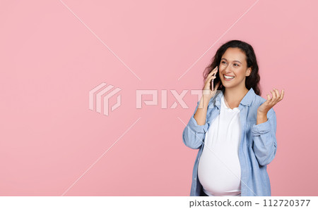 Cheerful pregnant woman have phone conversation on pink background Cheerful pregnant woman have phone conversation on pink background 112720377