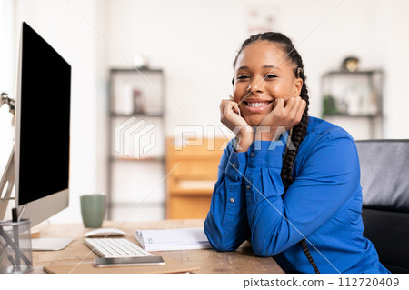 Contented black lady with braids at her computer desk at home 112720409