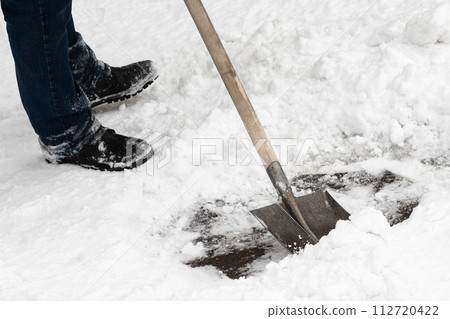 A skilled worker efficiently clears snow using an iron shovel with a sturdy wooden handle. Experienced professional worker quickly removes the snow following a snowfall. A skilled worker efficiently clears snow using an iron shovel with a sturdy wooden handle. Experienced professional worker quickly removes the snow following a snowfall. 112720422