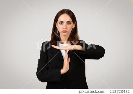 Stern young businesswoman with dark hair making a timeout gesture with a serious expression 112720481