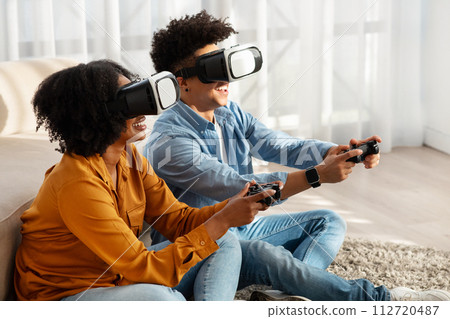 Exhilarated African American couple immersed in a virtual reality game 112720487