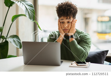 Stressed young black guy entrepreneur working at cafe 112720511