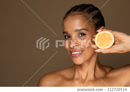 Smiling black middle aged woman with slice of orange 112720514
