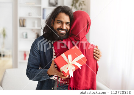 Happy Arab Man Embracing His Muslim Wife And Holding Gift 112720538