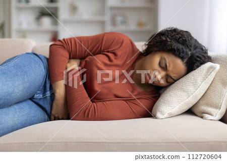 Menstrual Pain. Young Black Woman Suffering From Acute Abdominal Ache At Home Menstrual Pain. Young Black Woman Suffering From Acute Abdominal Ache At Home 112720604