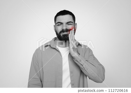 Black and white image of a man with a beard feeling dental discomfort Black and white image of a man with a beard feeling dental discomfort 112720616