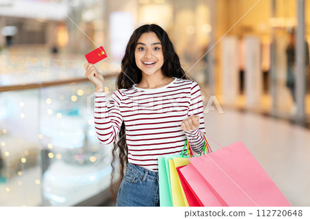 Cheerful woman with credit card, colorful bags at the mall Cheerful woman with credit card, colorful bags at the mall 112720648