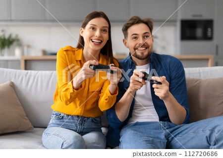 Joyful couple playing video games together on the couch 112720686