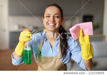 Joyful woman holding cleaning products, ready to clean Joyful woman holding cleaning products, ready to clean 112720695
