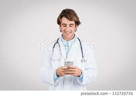 Happy male doctor texting on smartphone, having online consultation 112720738