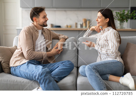 Happy couple engaging in a lively conversation on couch 112720785