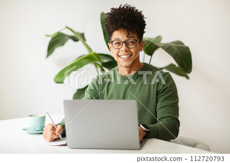 Cheerful stylish black guy freelancer working at cozy cafe Cheerful stylish black guy freelancer working at cozy cafe 112720793