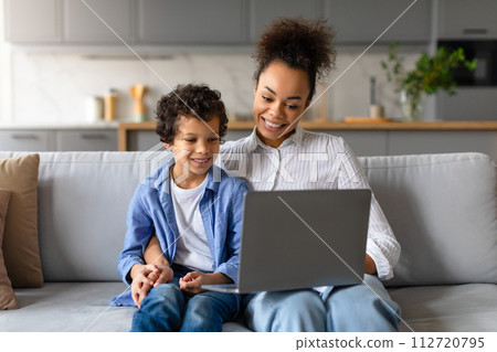 Black mother and son sharing moment with laptop at home 112720795