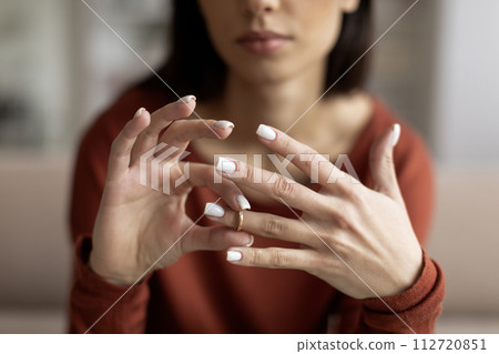Closeup shot of upset young woman taking off wedding ring at home 112720851