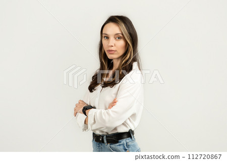 Stern looking young woman with arms crossed wearing a white blouse and jeans Stern looking young woman with arms crossed wearing a white blouse and jeans 112720867